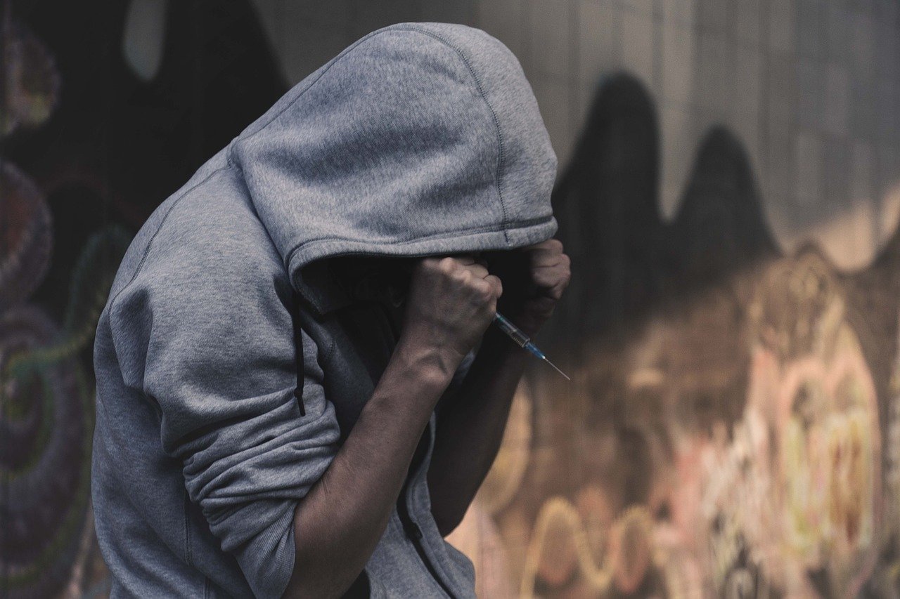 person in a hoodie with a syringe