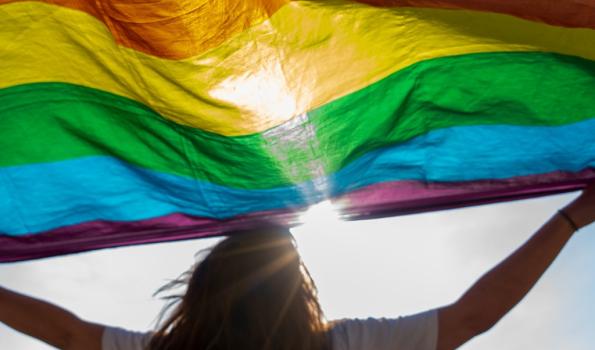 Woman holding up LGBTQ flag