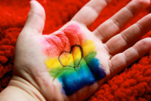 Heart inked over a rainbow flag on a hand